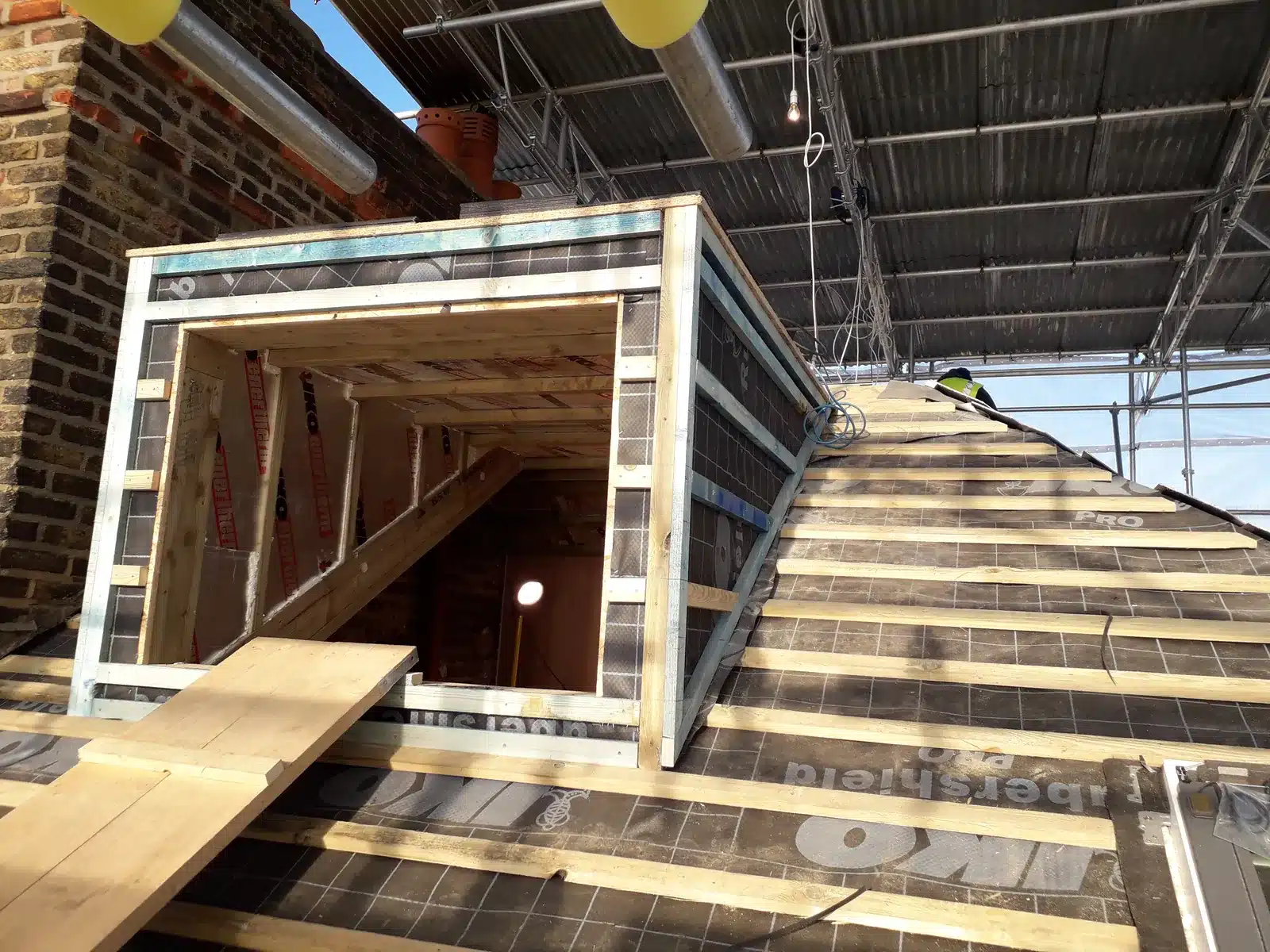 Timber dormer frame on a roof under a temporary scaffold roof during construction, Clapham SW4