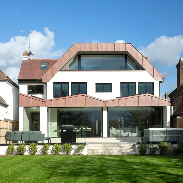 The back of the house after: a copper-clad gable with a wide window, and full-width glazing to the garden