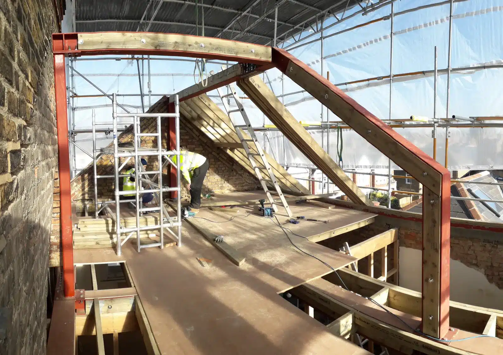 Steel and timber frame under construction at roof level on an AURA project in Clapham, with scaffolding around it.