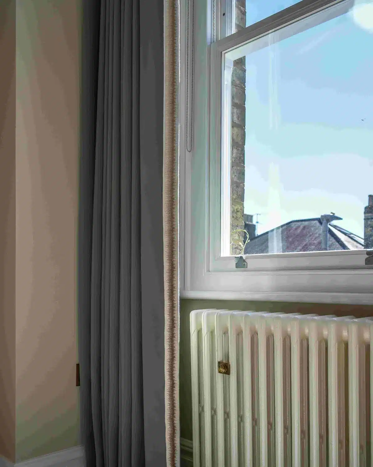Sash window with a cast-iron style radiator and curtain in the renovated main house, Putney SW15