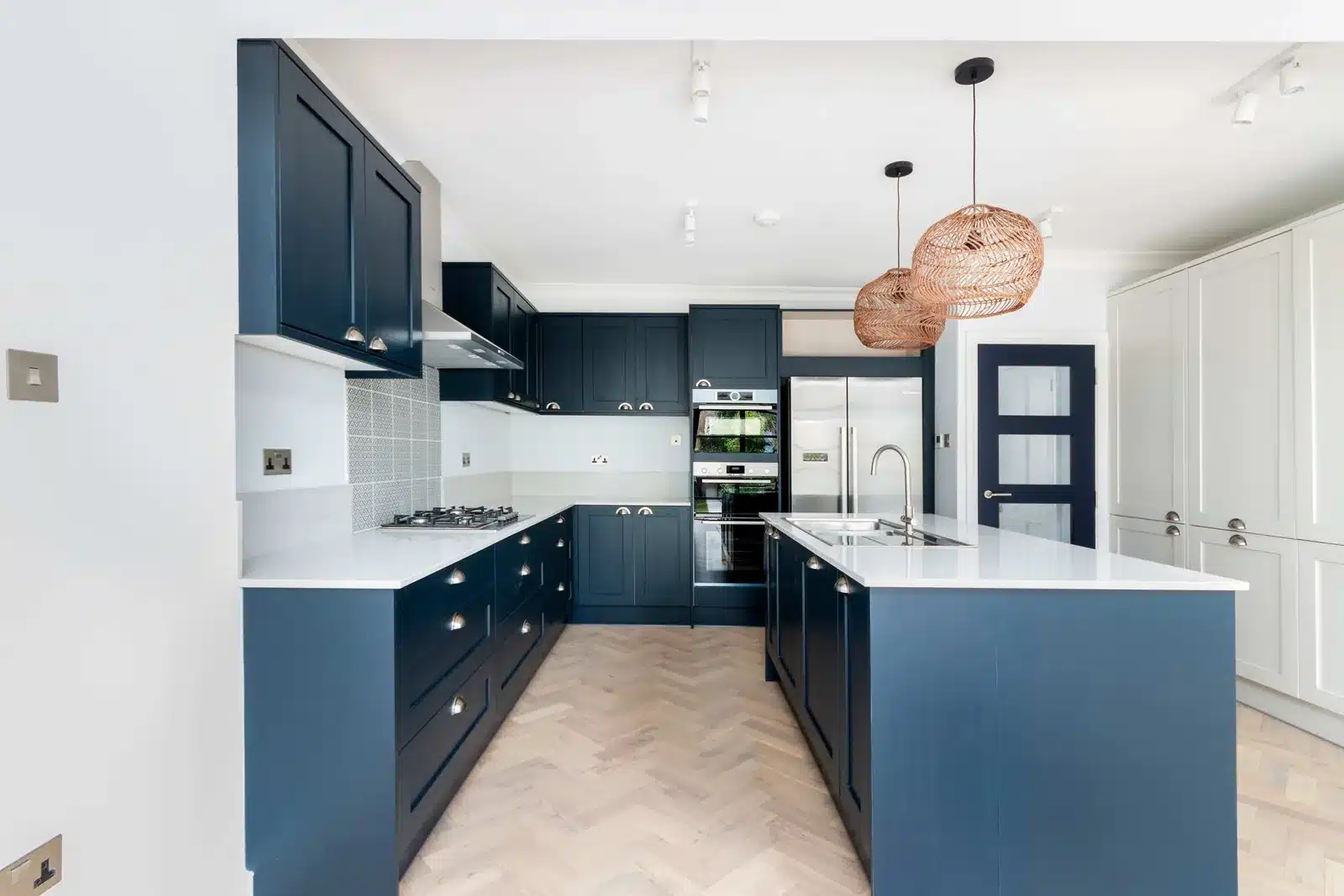 Open-plan kitchen in a rear extension with navy cabinets and a central island, Wimbledon